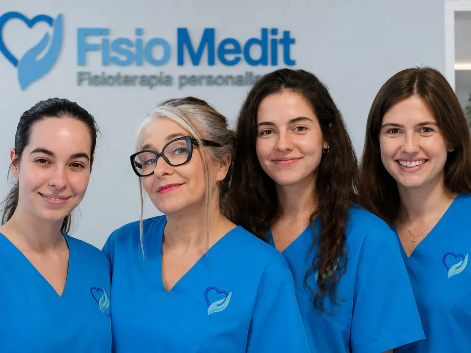 Cuatro fisioterapeutas del equipo de suelo pélvico, con el pijama azul, delante del logo de FisioMedit